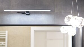 A modern bathroom with two white sinks, a large mirror, and a hanging light fixture.