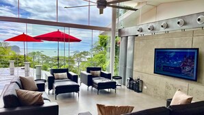 Un salón moderno con sofás de cuero, sombrillas rojas y una gran pantalla de televisión.