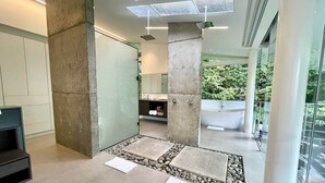Un baño moderno con una bañera independiente, una cabina de ducha con paredes de vidrio y un espejo grande.