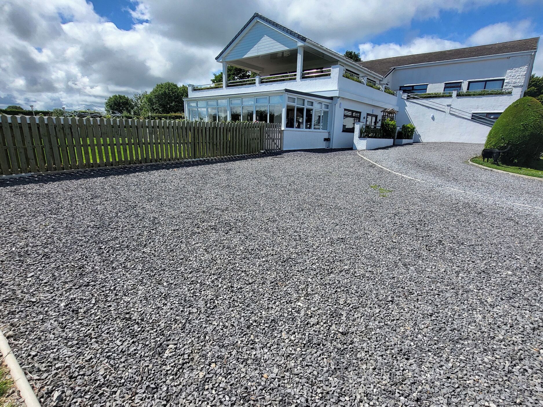A two-story building with a gravel driveway and a wooden fence.