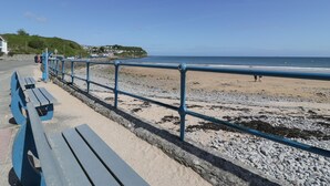 Eine Uferpromenade mit Bänken und Geländer mit Blick auf den Strand.