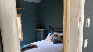 A bedroom with a bed, a nightstand, a window, and a ceiling fan.