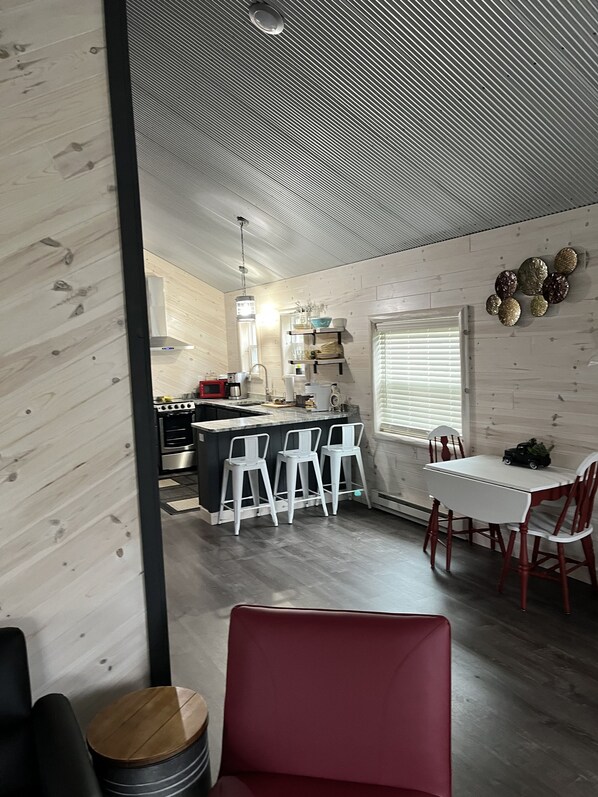 A modern kitchen with a central island, bar stools, and a dining table with chairs.