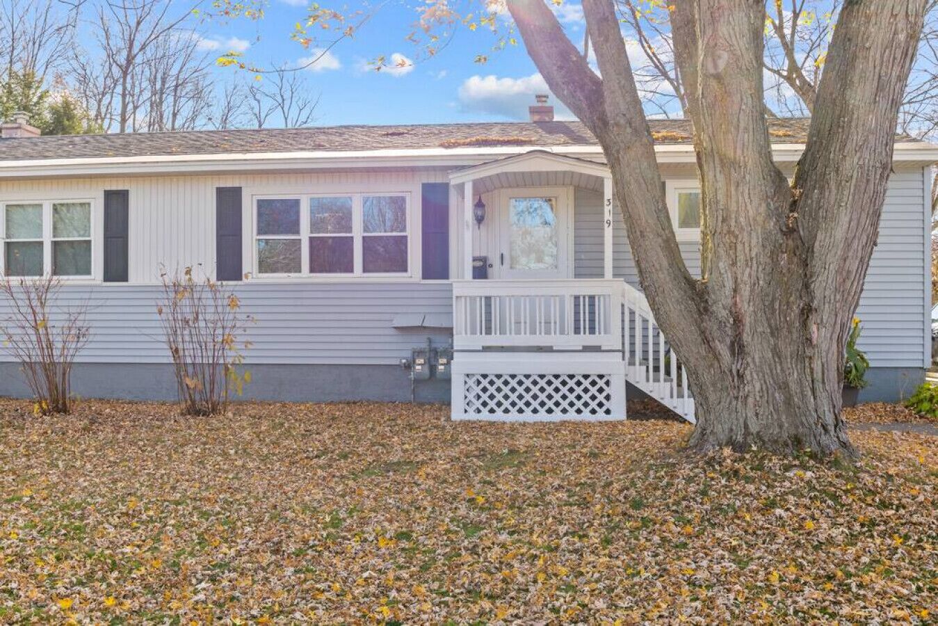 A single-story house with a front porch, a visible chimney, and a tree in the foreground.