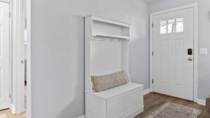 A hallway with a white bench, a door, and a rug. - Lovely 2-Bedroom Condo, Close to Burlington/Airport! (South Burlington)