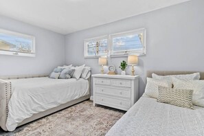 A bedroom with two beds, a nightstand, and a dresser.