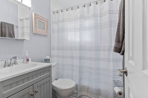 A bathroom with a white sink, a toilet, a shower curtain with horizontal stripes, and a towel hanging on the wall.