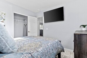 Une chambre à coucher comprenant un lit, une armoire, un téléviseur à écran plat et une plante en pot.