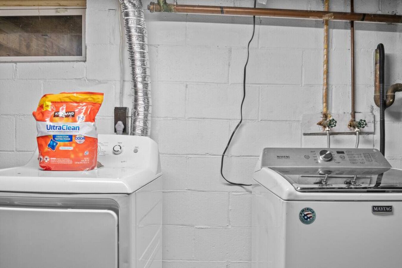 Un área de lavandería con lavadora y secadora, un paquete de detergente UltraClean y una secadora Maytag.