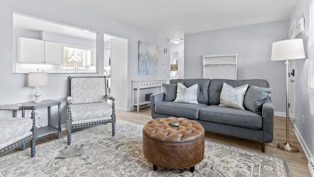 A modern living room with a grey sofa, a patterned rug, a wooden coffee table, and a leather ottoman. - Lovely 2-Bedroom Condo, Close to Burlington/Airport! (South Burlington)