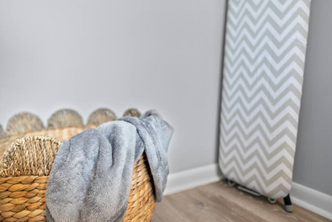 Un panier en osier avec une serviette grise, un panier tressé et un rideau à motifs chevrons gris et blancs.