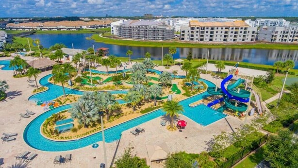 A resort with a large swimming pool, palm trees, and a water slide. - SUMMER SALE! Storey Lake 3BDRM (Kissimmee)