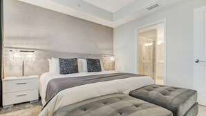 A modern bedroom with a large bed, two bedside tables, and a built-in bench. - SUMMER SALE! Storey Lake 3BDRM (Kissimmee)