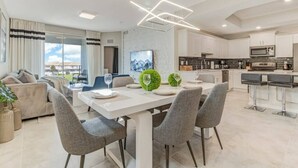 A modern living room with a dining area, a kitchen, and a balcony with curtains. - SUMMER SALE! Storey Lake 3BDRM (Kissimmee)