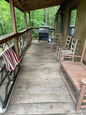 Eine Holzterrasse mit Grill, Stühlen und einem überdachten Bereich.