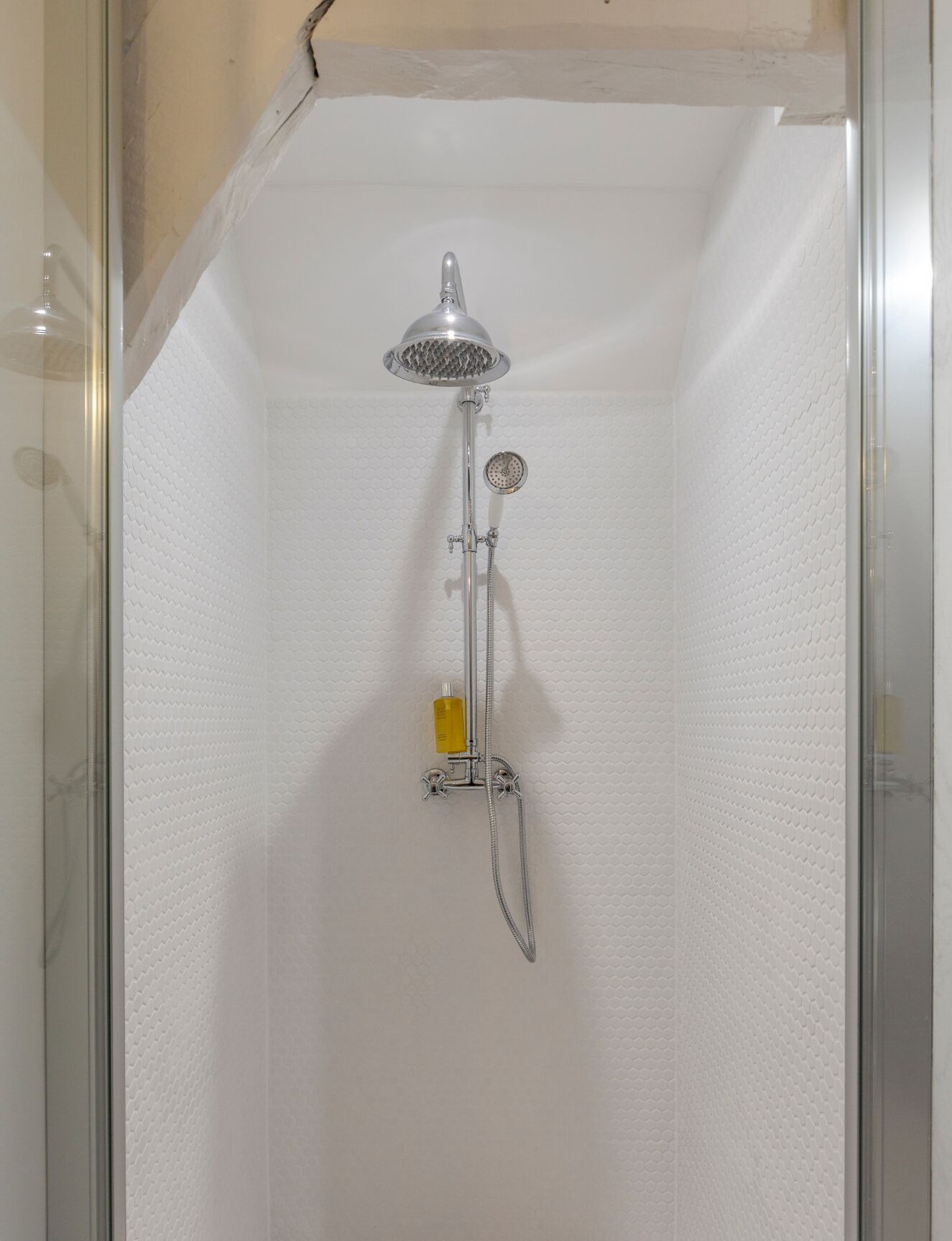 A shower with a handheld showerhead, a handheld showerhead, and a handheld showerhead.