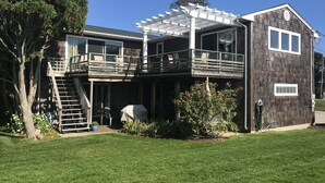Une maison à deux étages avec un patio couvert, un escalier et un jardin.