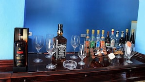 A bar with various bottles of liquor and empty glasses on a wooden bar counter. - Hostal La Pianista TRINIDAD (Trinidad)
