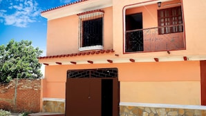 A two-story building with a brown gate, a balcony with decorative iron railings, and a stone base. - Hostal La Pianista TRINIDAD (Trinidad)