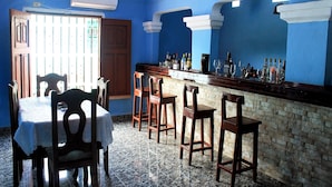 A bar area with a counter, bar stools, and a table with chairs. - Hostal La Pianista TRINIDAD (Trinidad)