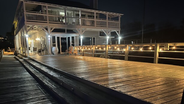 A dock office with a wooden deck, outdoor seating, and a sign indicating it is a marine mart.