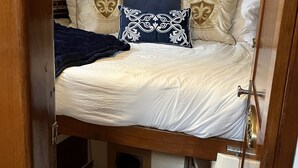 A compact, wooden bunk bed with a headboard, multiple pillows, and a woven basket.