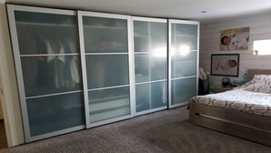 A bedroom with a large sliding glass closet, a bed with patterned bedding, and a wall with a framed picture. - Lovely loft with private pool (Le Creusot)