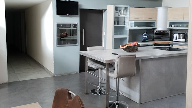 A modern kitchen with a central island, bar stools, and a dining table with chairs. - Lovely loft with private pool (Le Creusot)