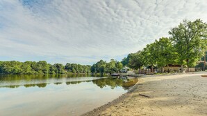 En vacker utsikt över sjön med en sandstrand, en brygga och ett hus med en veranda.