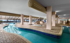 An indoor swimming pool with clear blue water, tiled edges, and a sunroof.