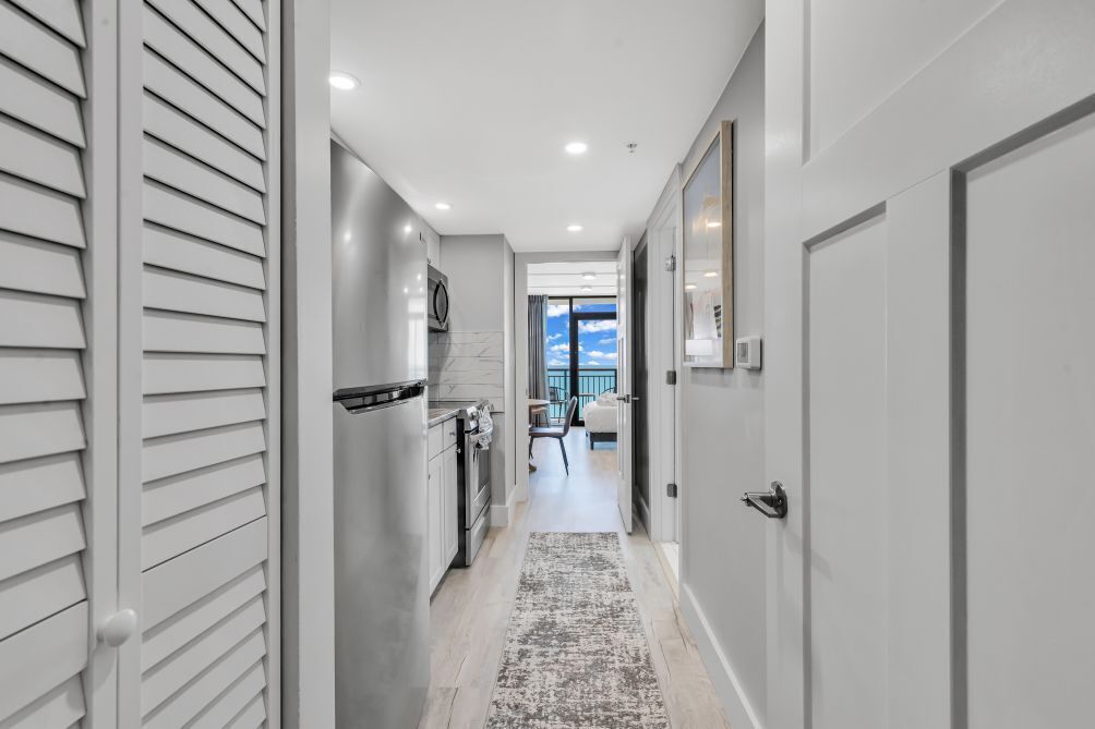 A hallway with a kitchen area, a dining area, and a view of the sky.