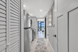 A hallway with a kitchen area, a dining area, and a view of the sky.