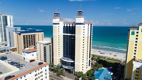 A high-rise hotel with multiple balconies overlooking a beach.