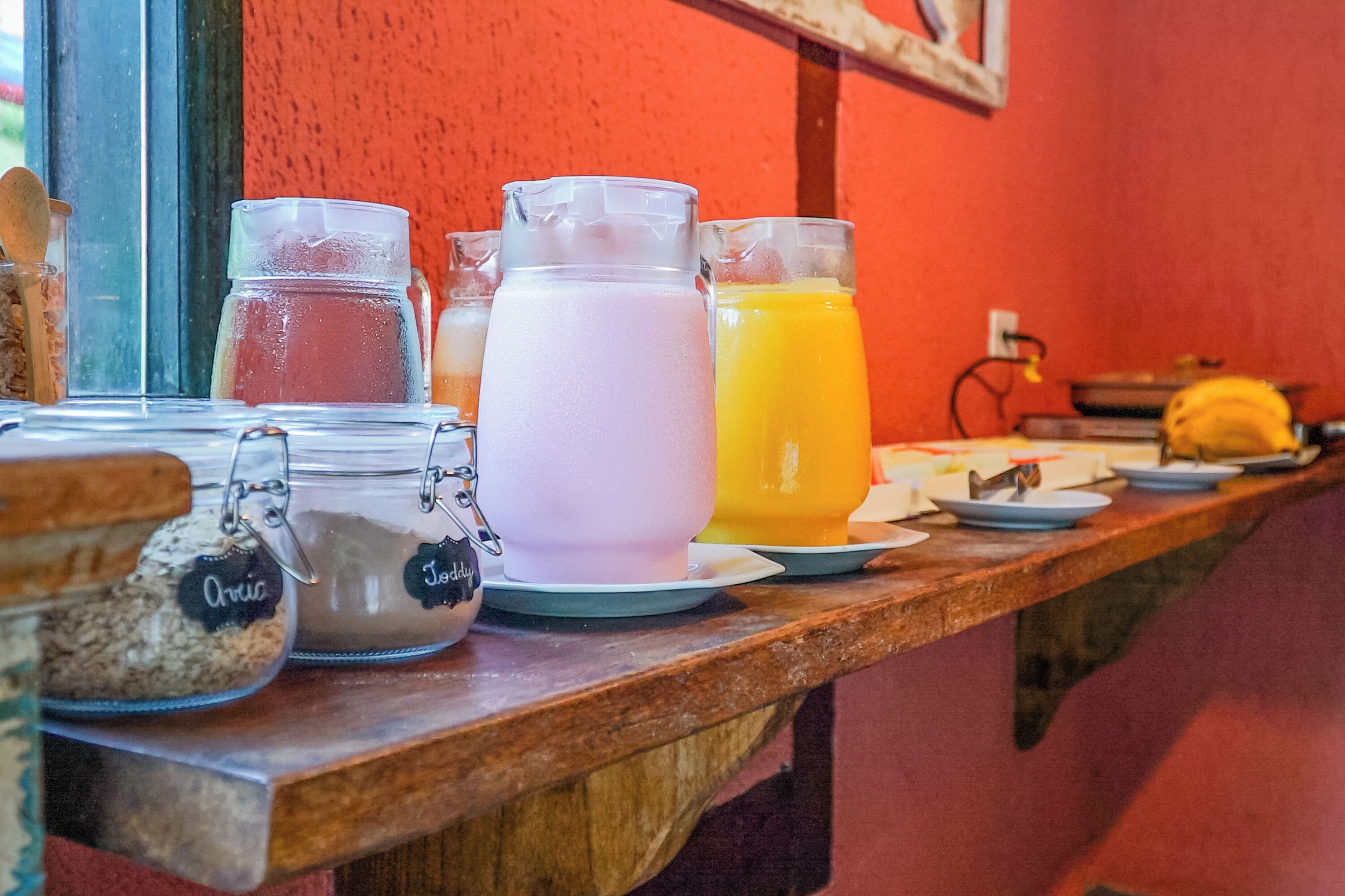 Una barra de desayuno con varios recipientes de comida y bebidas, incluyendo frascos etiquetados 'Aric' y 'Jolly'.