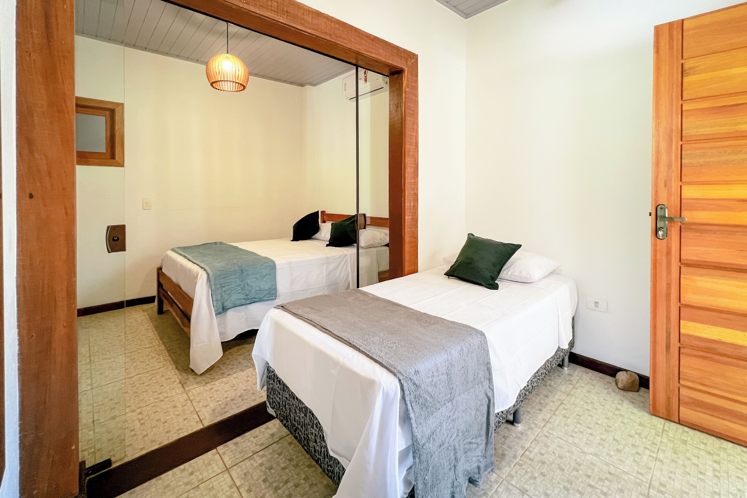 A room with two beds, a wooden door, and a mirror.
