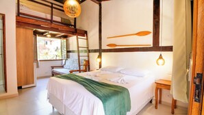 A bedroom with a bed, wooden headboard, bedside tables, and a window with a view. - VELINN Pousada Canoa Ilhabela (Ilhabela)