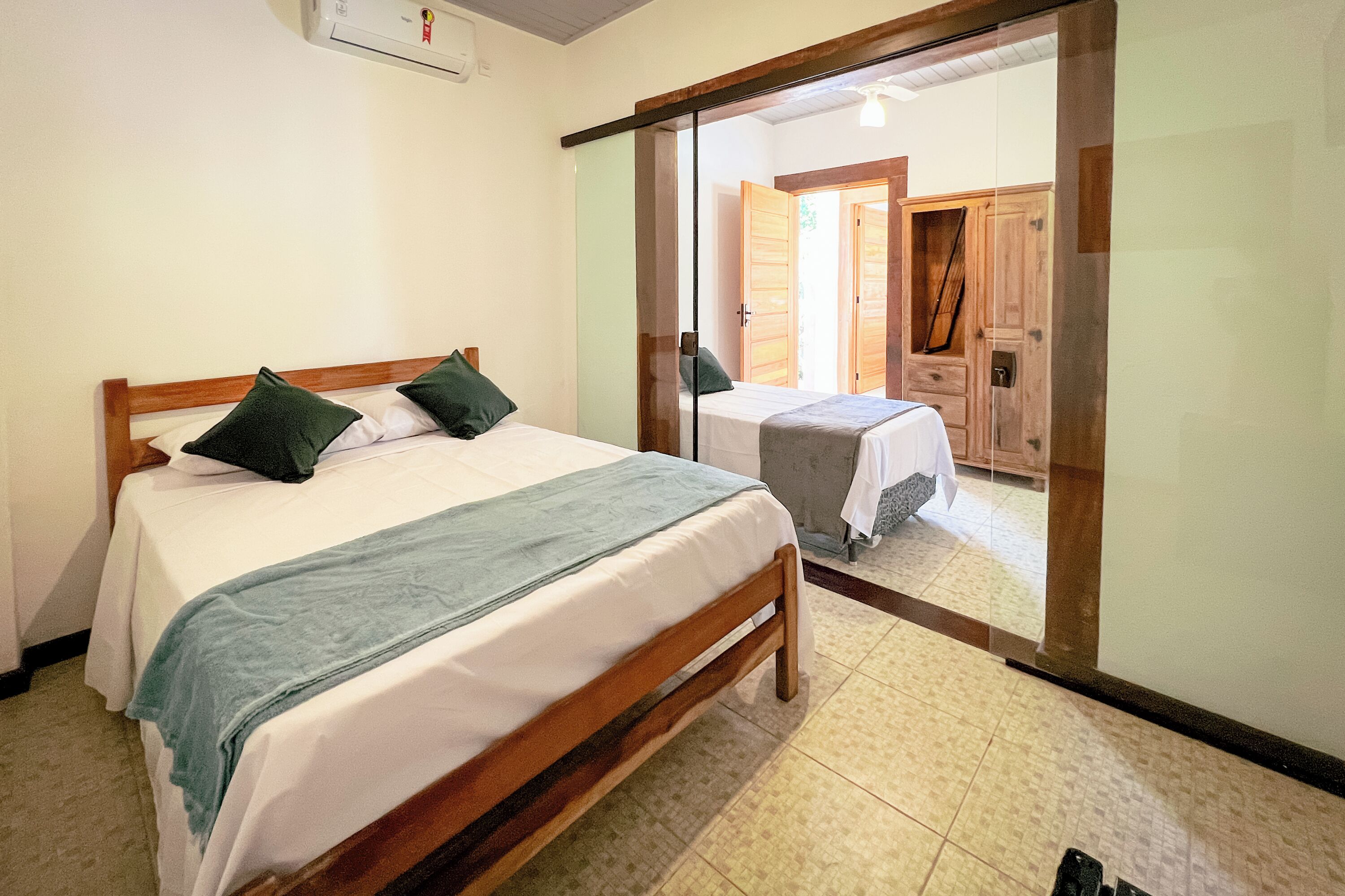 Un dormitorio con dos camas, cabeceros de madera y una puerta corrediza de vidrio que da a otra habitación.