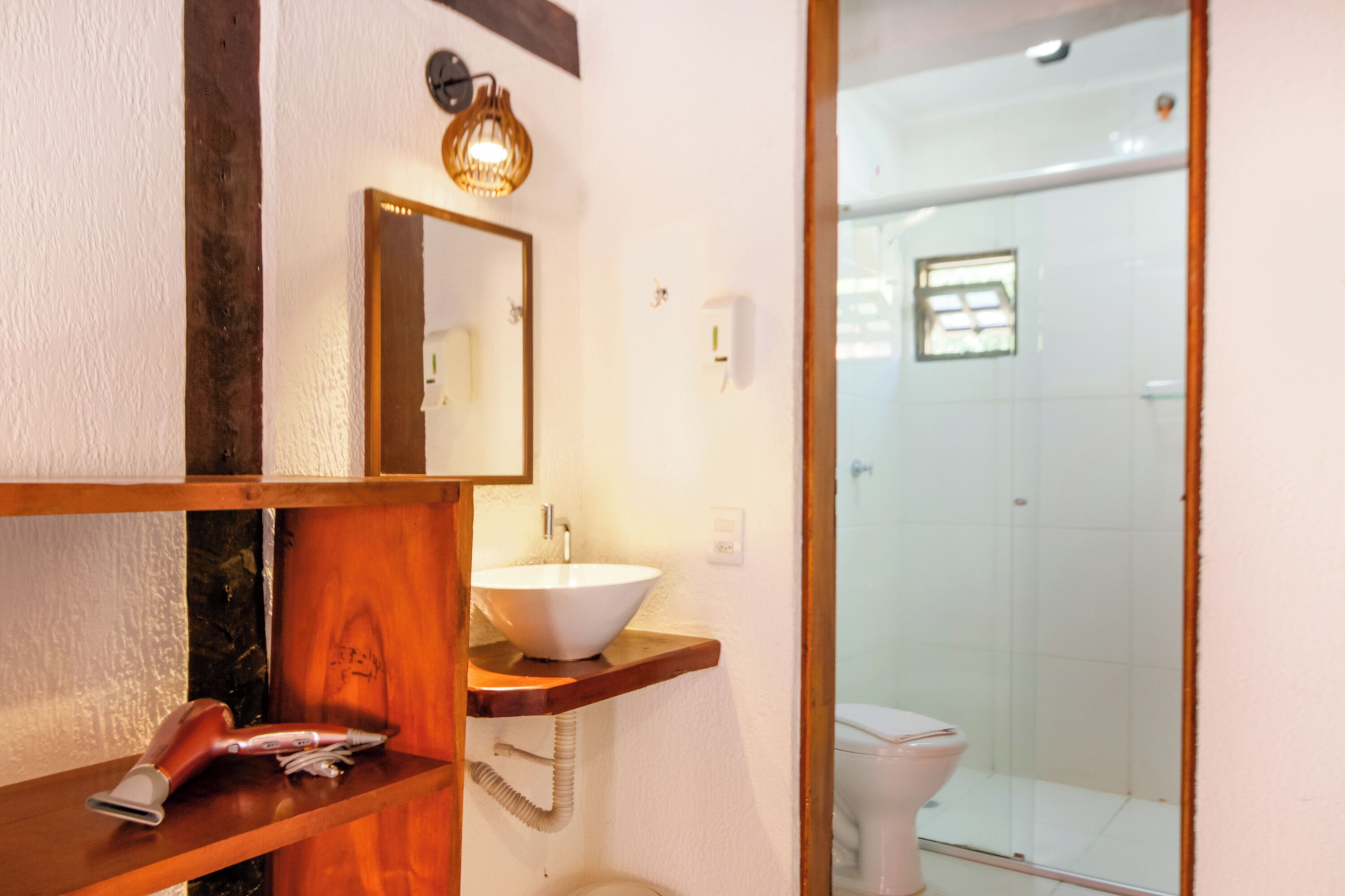 A bathroom with a wooden vanity, a white sink, a mirror, and a glass shower enclosure.