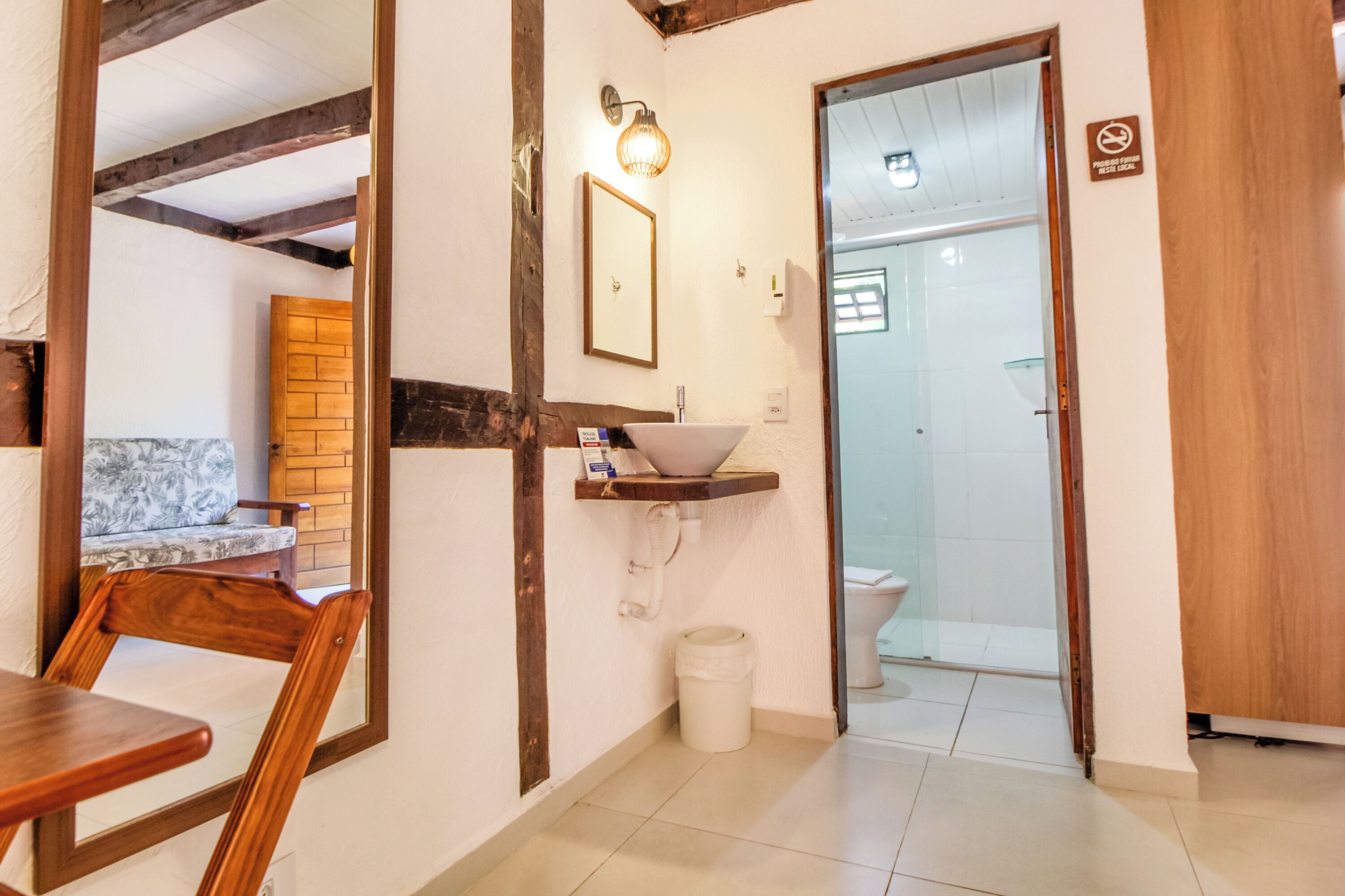 A bathroom with a wooden-framed mirror, a sink with a white basin, and a toilet.