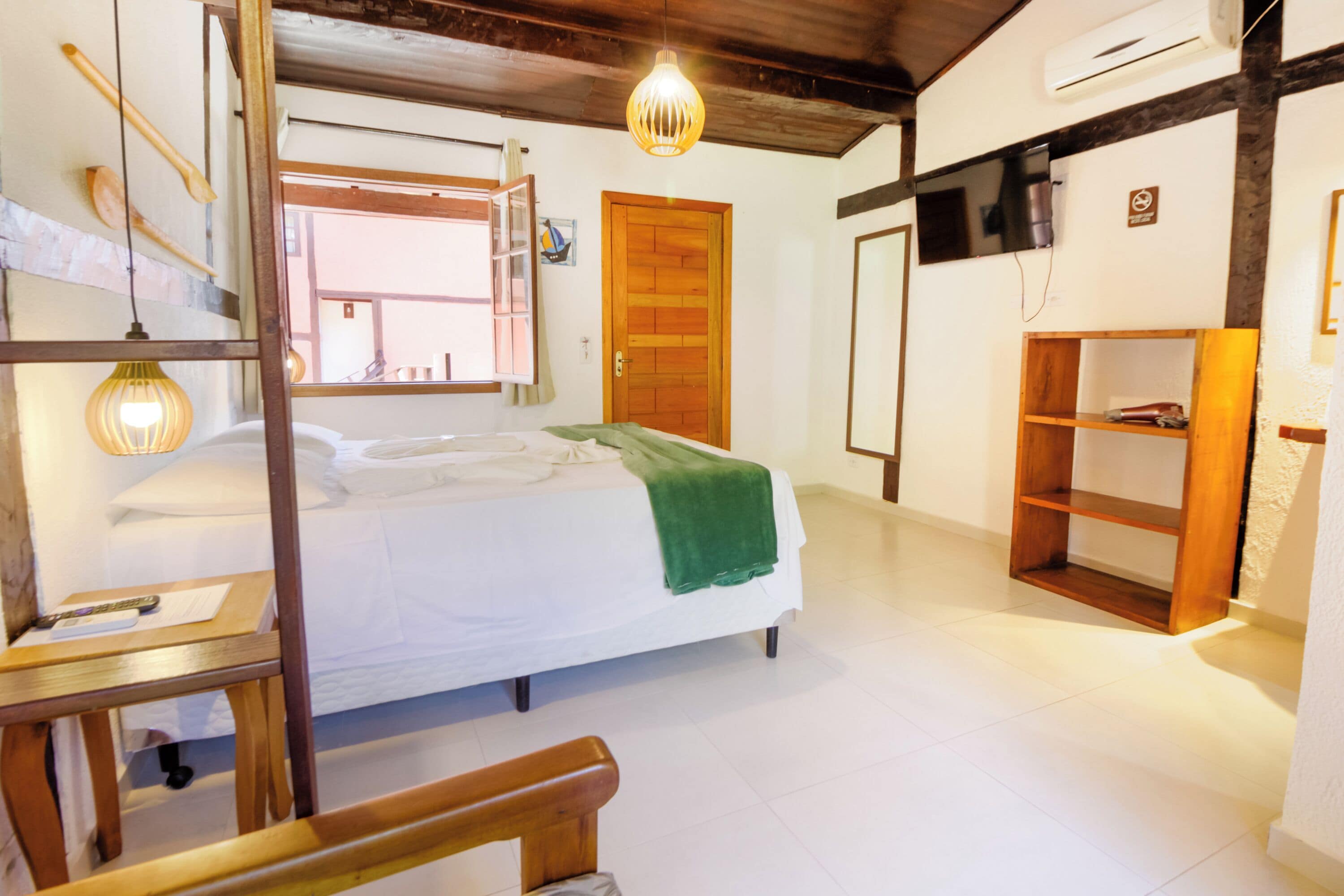 Ein Schlafzimmer mit einem Bett, einem Holzstuhl, einem Regal und einer Pendelleuchte.