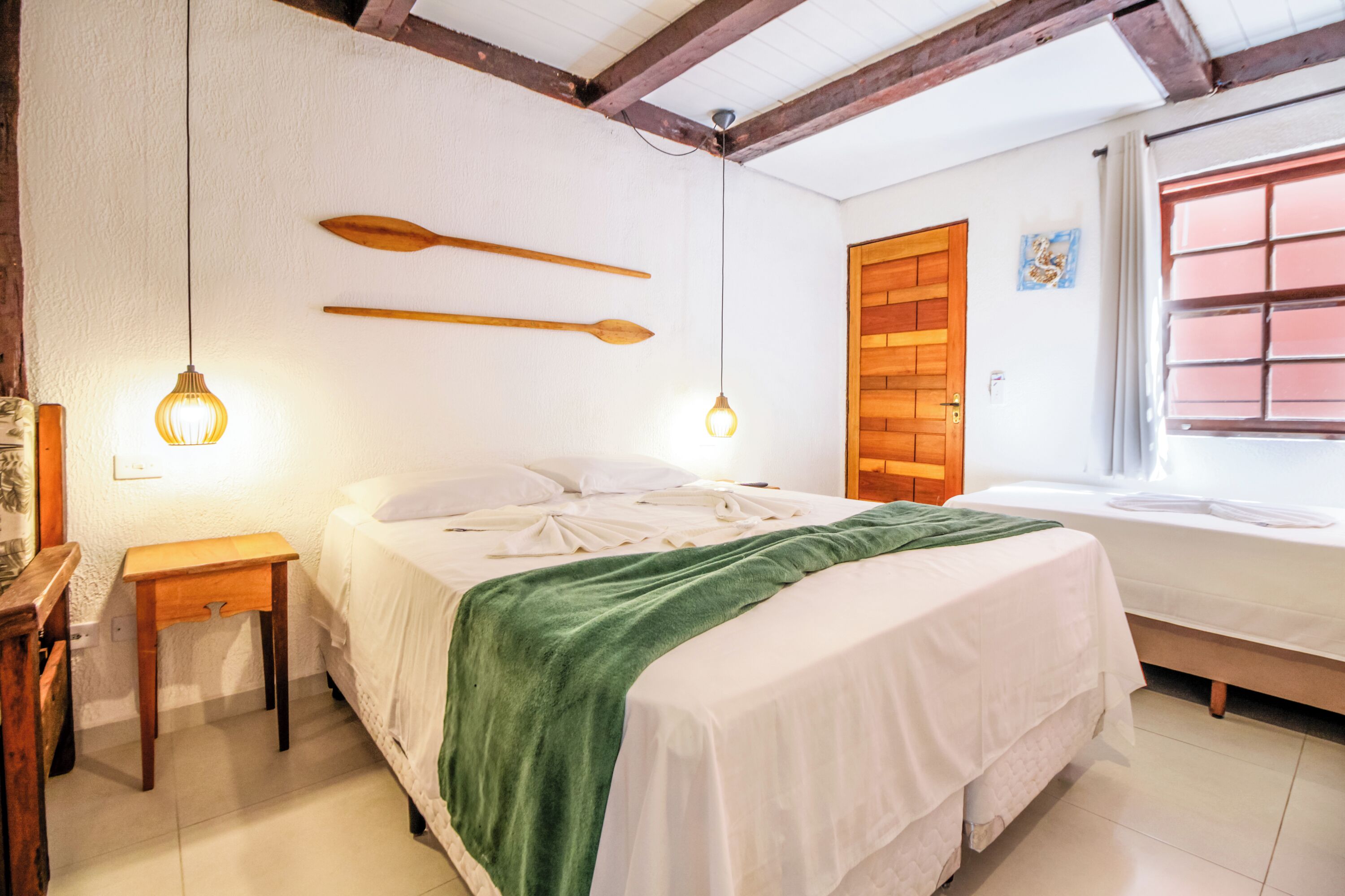 Ein Schlafzimmer mit einem Bett, Nachttischen, einer Holztür und einem Fenster mit Jalousien.