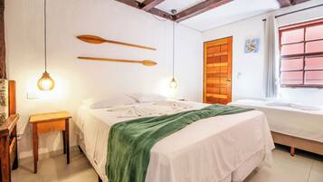 A bedroom with a bed, bedside tables, a wooden door, and a window with blinds.