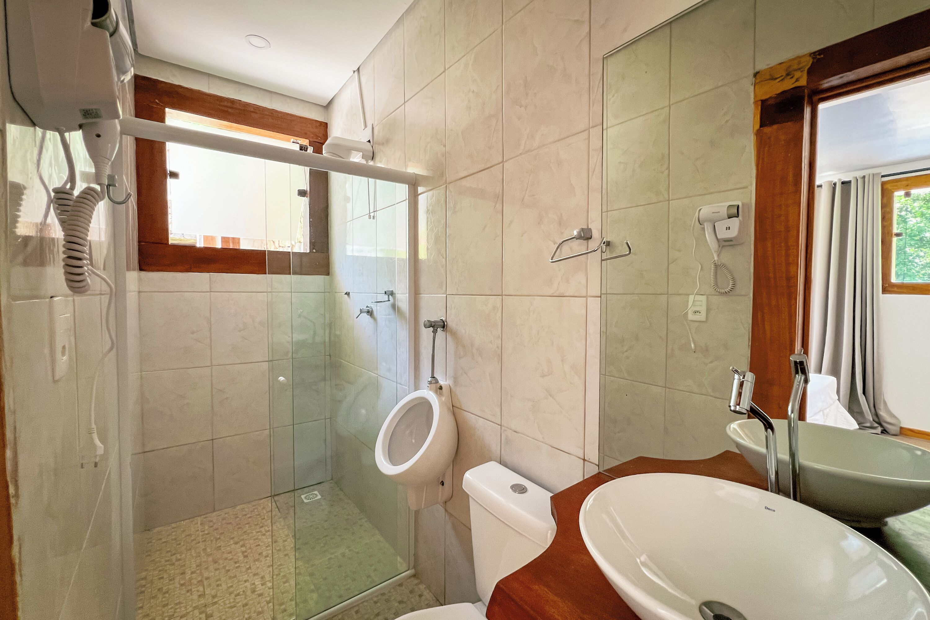 A bathroom with a glass shower enclosure, a toilet, a sink, and a mirror.