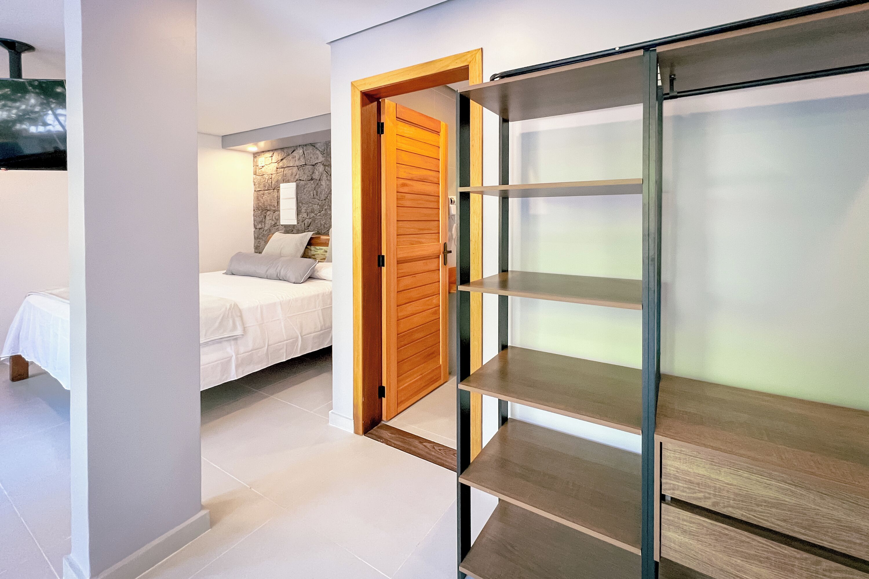 Un dormitorio moderno con cama, puerta de madera y estantería empotrada.