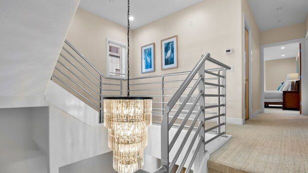 A modern interior with a staircase, a chandelier, and framed artwork on the walls. - Luxury Townhome with a Rooftop Deck! - Changing Channels (Siesta Key)