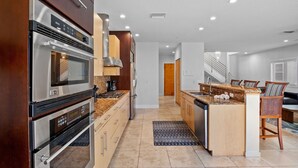 A modern kitchen with stainless steel appliances, a wooden island, and a built-in dishwasher. - Luxury Townhome with a Rooftop Deck! - Changing Channels (Siesta Key)