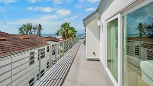 A balcony with a view of the sea, a white building, and a palm tree. - Luxury Townhome with a Rooftop Deck! - Changing Channels (Siesta Key)