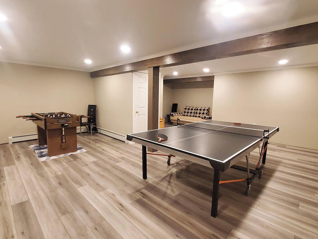 Una habitación con mesa de ping pong, mesa de futbolín y un sofá.