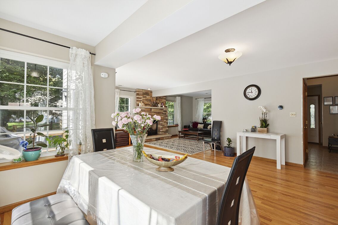 A spacious living room with a dining area, a fireplace, and a view of the outdoors.