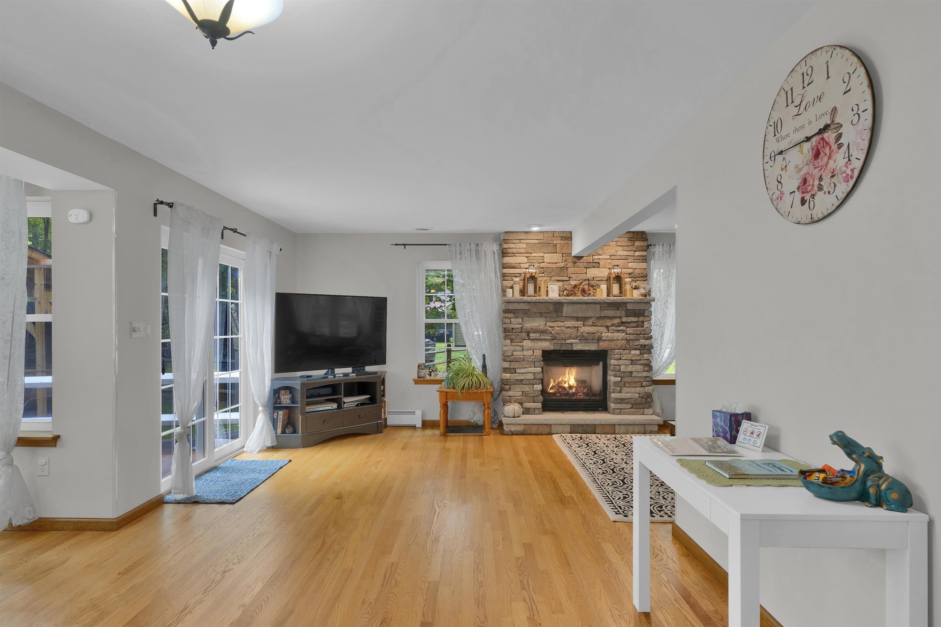 Un salon avec une cheminée, un téléviseur et une horloge au mur.